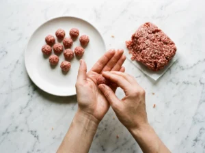 Hands shaping raw ground meat